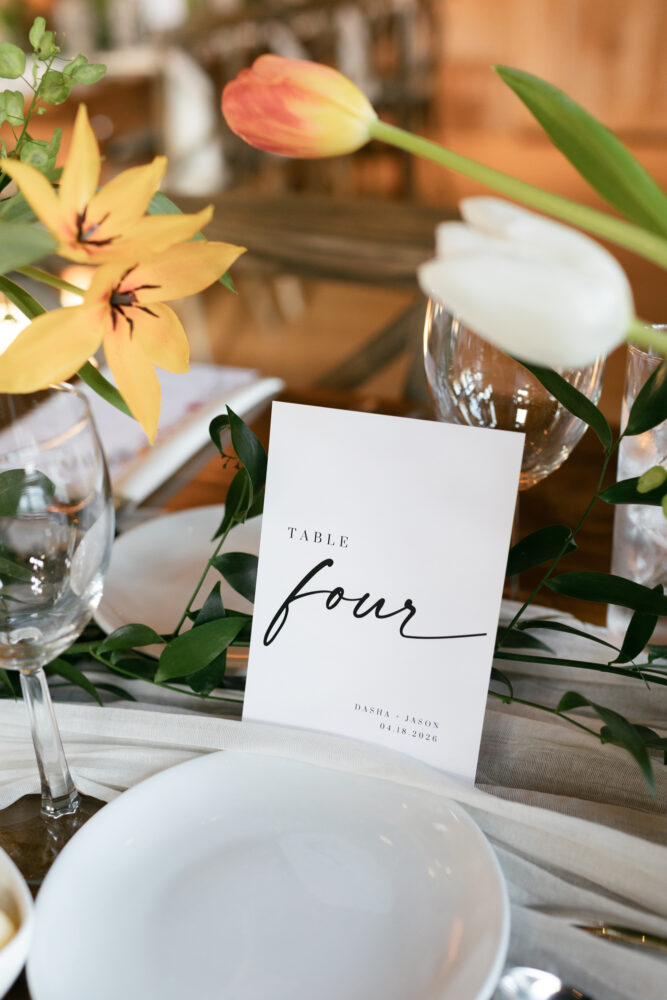 Wedding reception place card reading Table Four amid a floral table setting with yellow tulips and glassware