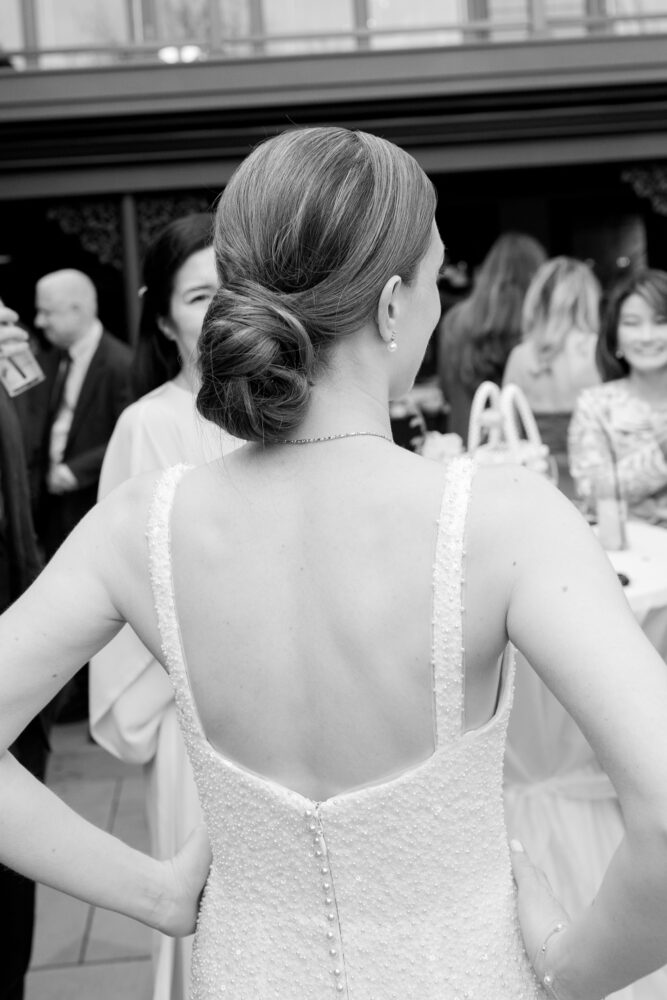 Woman seen from behind wearing a beaded low back gown with an elegant bun at a social event