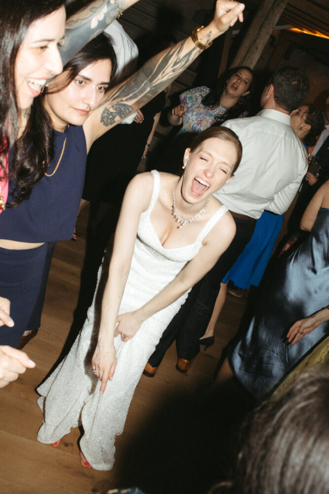 Bride in a sparkling white dress dancing with friends at a lively party