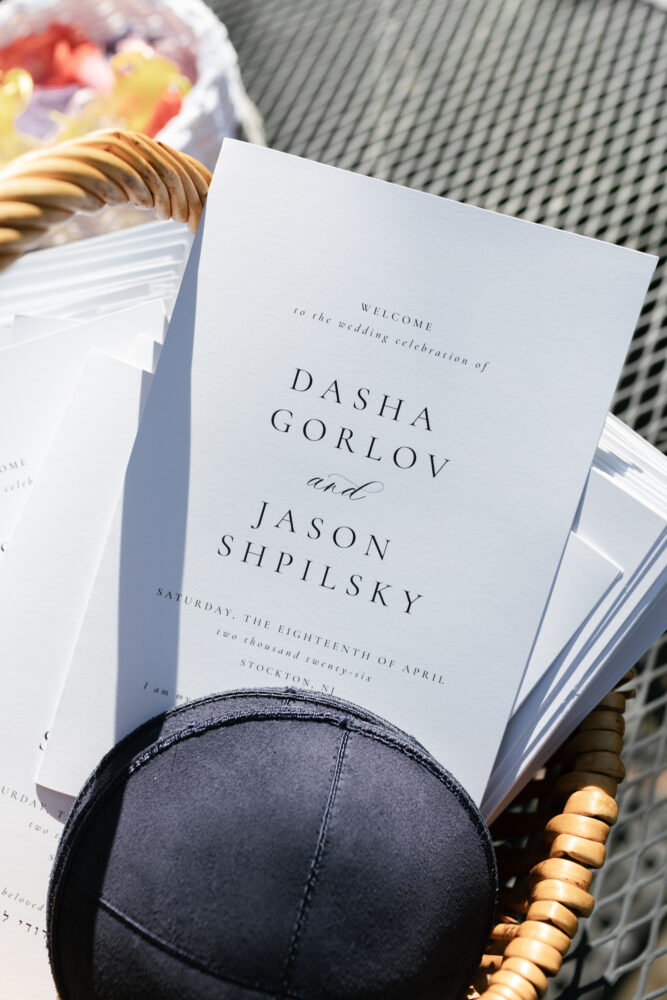 Wedding invitation in a wicker basket with a formal script displaying names Dasha Gorlov and Jason Shpilsky